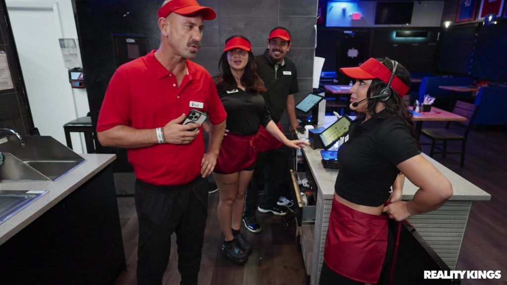 Three fast food employees talking to a manager behind the counter