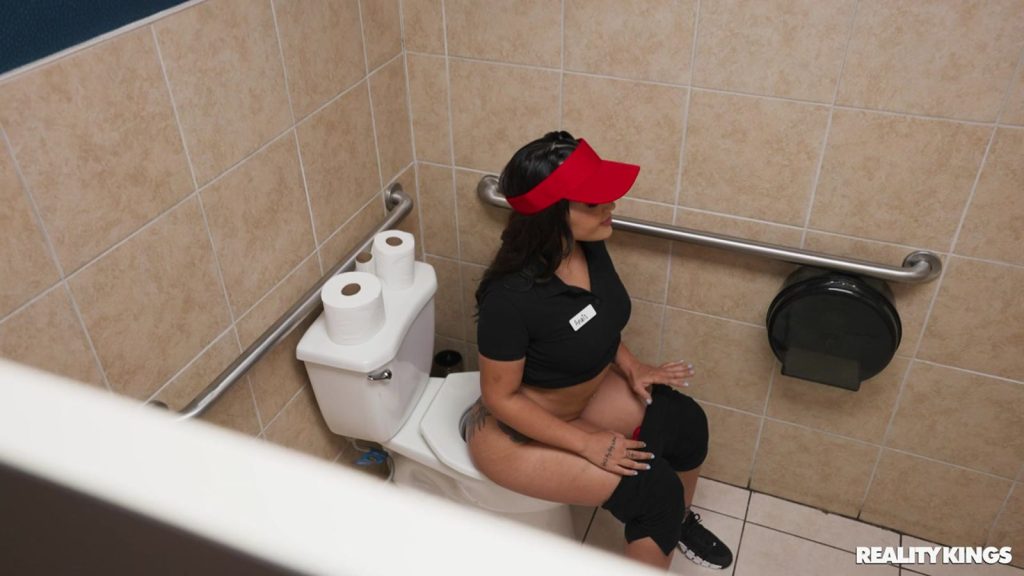 Looking down on a girl sitting on a toilet with her pants down