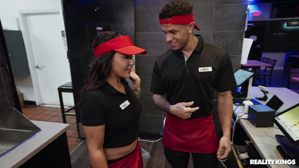 Side view of girl and a man wearing uniforms behind the counter at a fast food restaurant