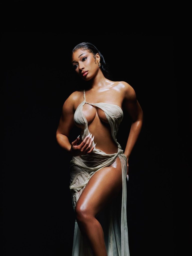 Frontal view of Megan Thee Stallion in a skimpy wet dress against a black background