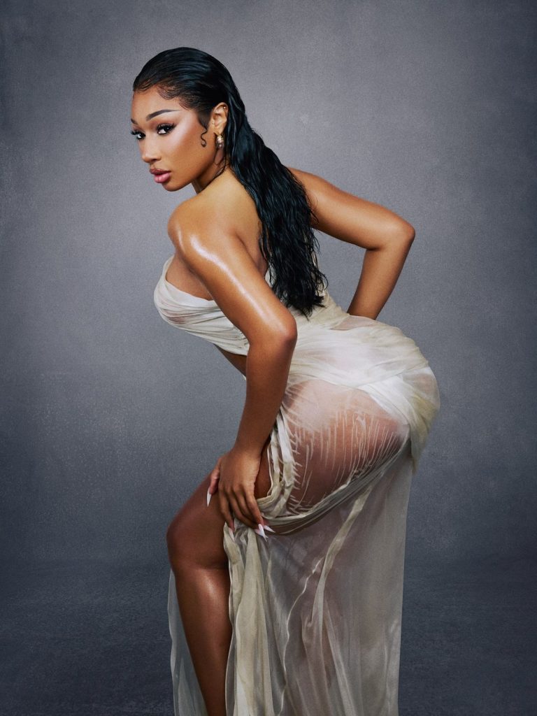Megan Thee Stallion lean forward and sticks her butt out while posing on her side in a wet dress