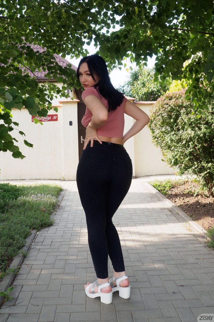 Girl posing outdoors with her backside turned looking back over her shoulder