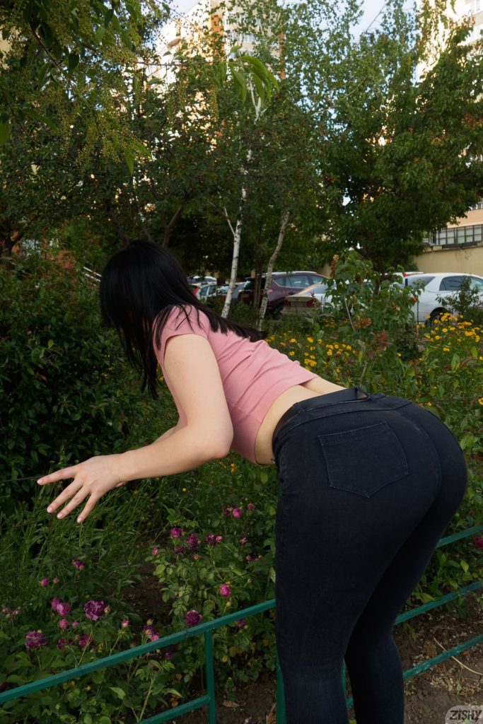 View from behind of girl bending over towards bushes