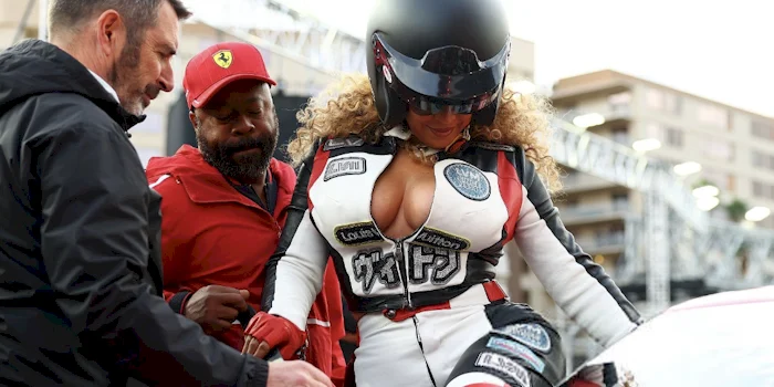 Close up of Beyonce showing cleavage in a racing outfit while she climbs into a car