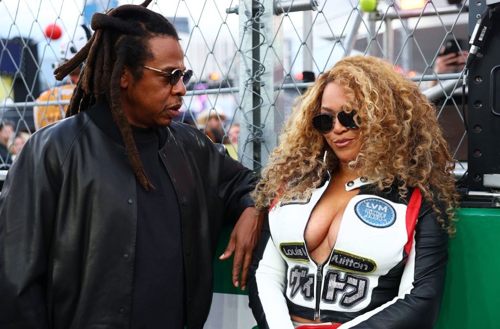 Close up of Jay-Z looking at Beyonce who is showing cleavage in a racing outfit
