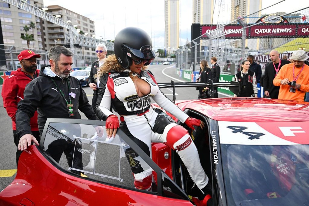 Horizontal view of Beyonce wearing a racing outfit and helmet while climbing into a racing car