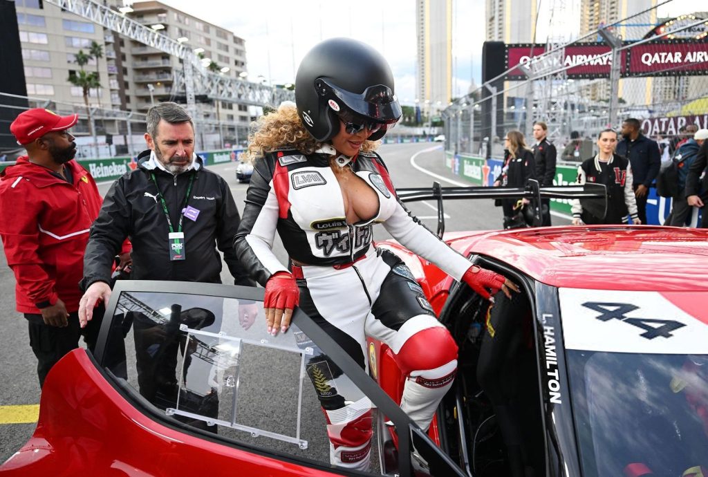 Closer view of Beyonce wearing a racing outfit and helmet while climbing into a racing car