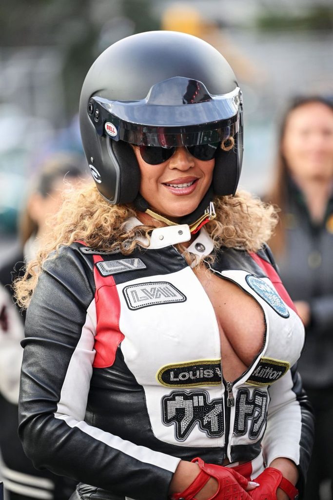 Close up of Beyonce's chest and face as she smiles wearing a racing outfit and helmet