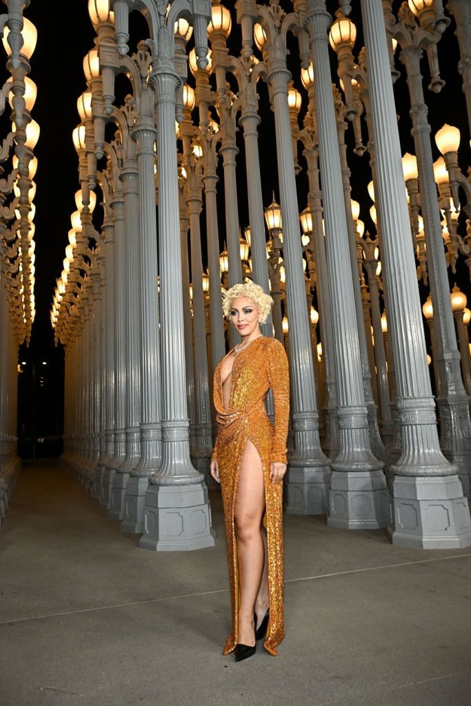 Very far away view of Doja Cat posing at an angle in front of tall street lights