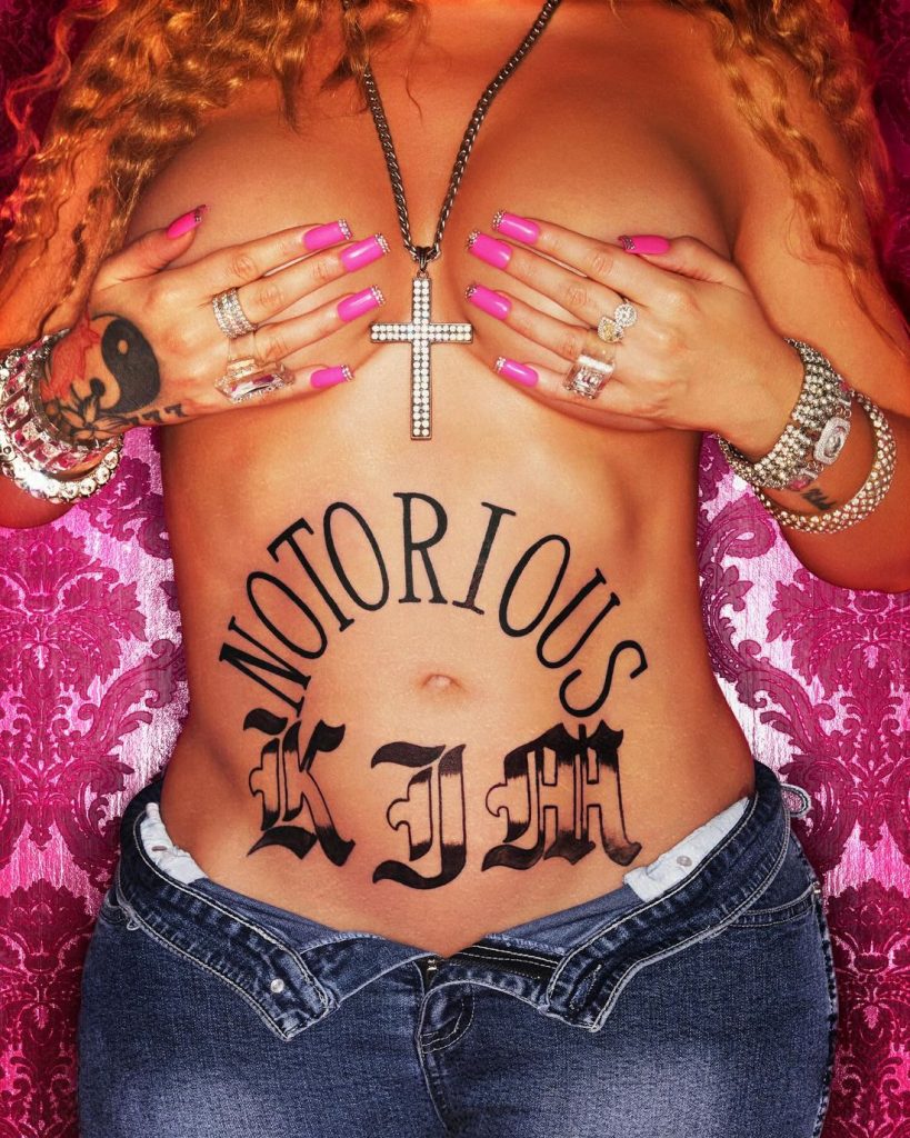 Close up of Latto covering her breasts while dressed up as Lil' Kim