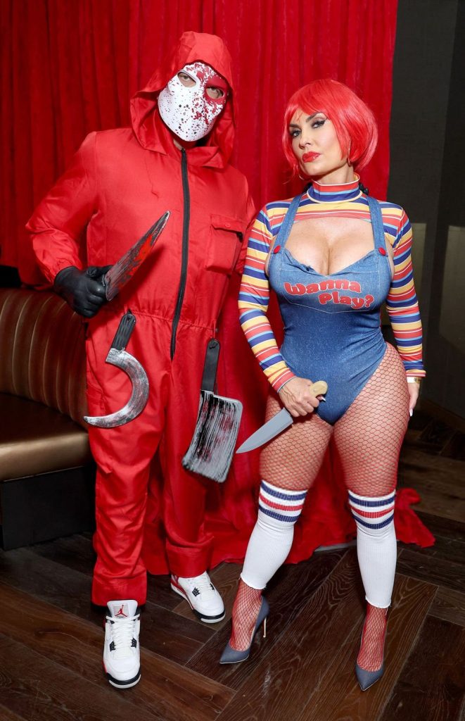 Full body front view of  woman and man posing in Halloween costumes and holding knives