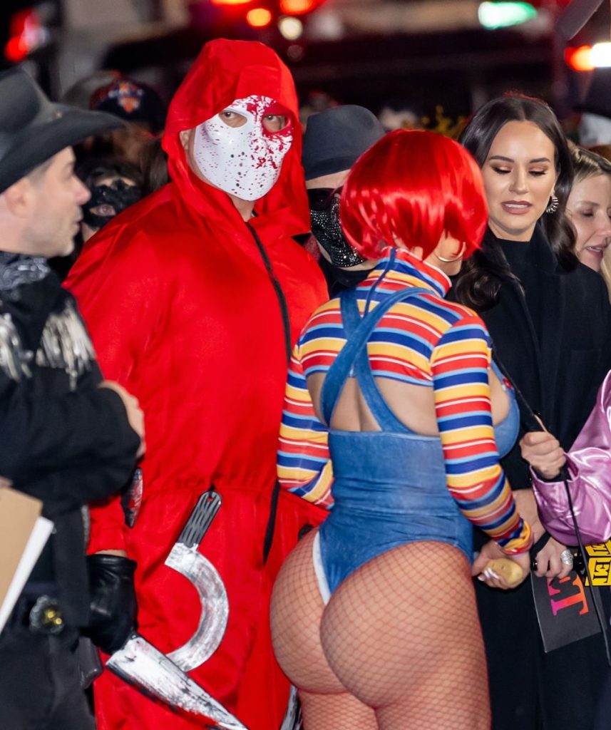 Backside view of curvy woman in a Chucky costume among a crowd at a party