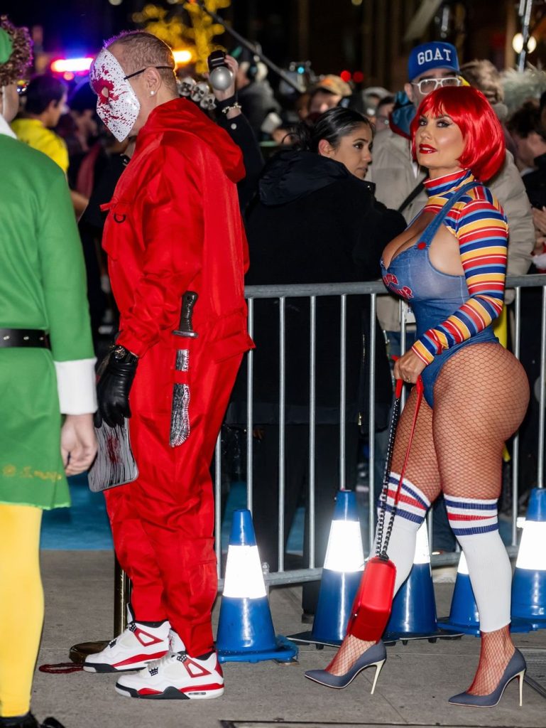 Side view of woman in a Chucky costume walking behind a man dressed as a murderer