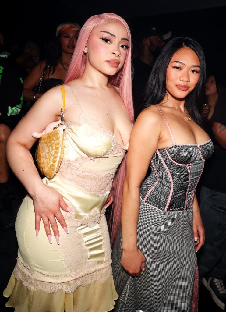 Frontal view of Ice Spice and Asian girl posing to their sides at a party