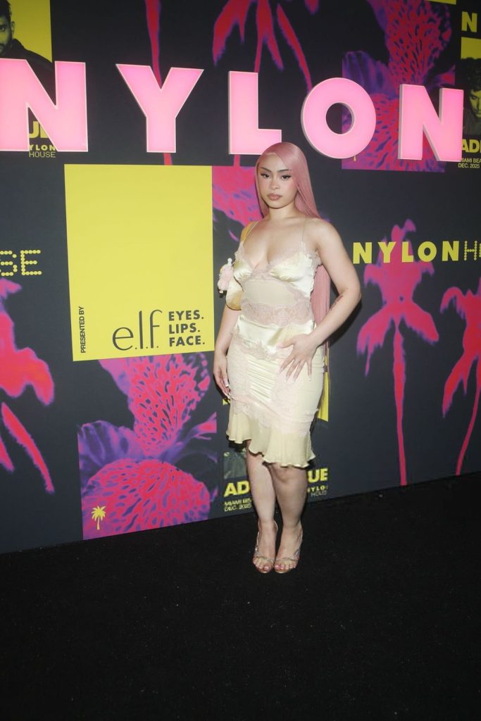 Far away side angle view of Ice Spice posing underneath NYLON sign