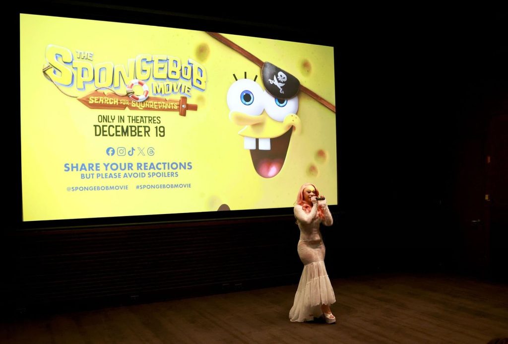 Far away view of Ice Spice on stage in front of a screen with SpongeBob on it