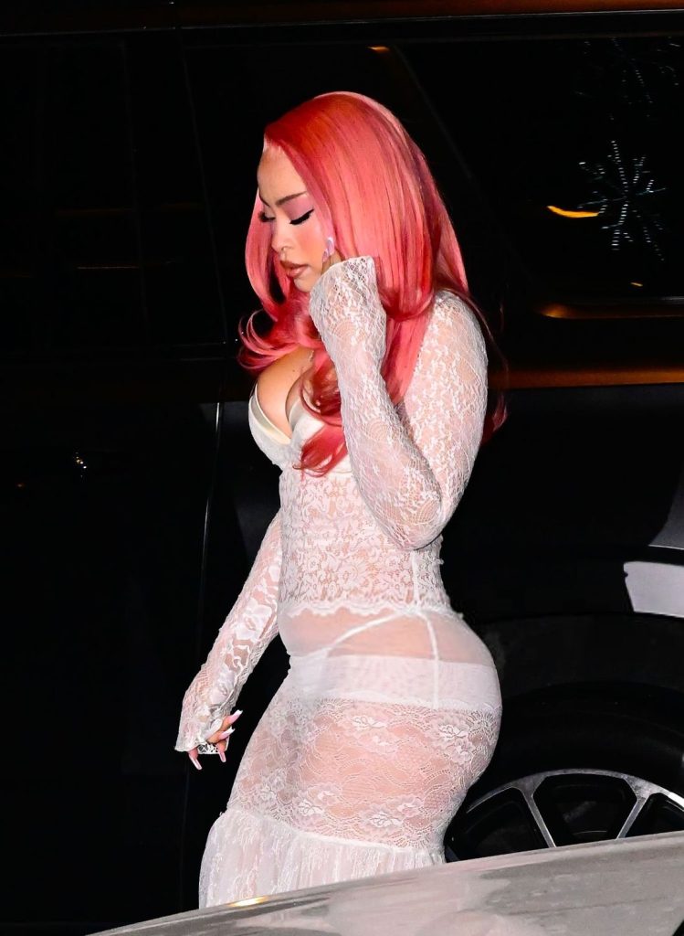 Side view of Ice Spice fixing her figure while walking between cars