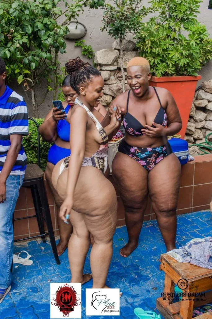 Full body side view of multiple thick black women in bikinis smiling and laughing at a party