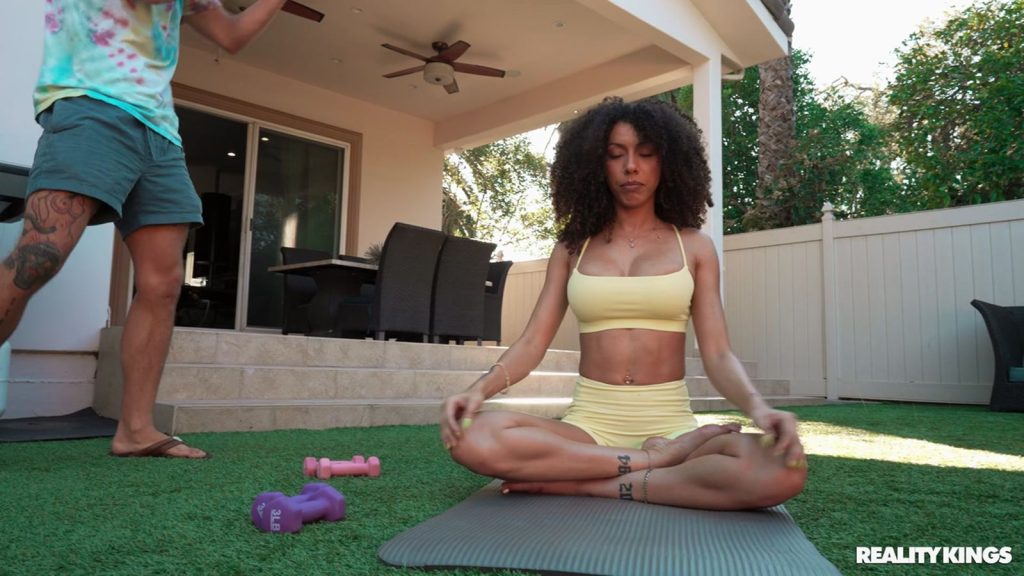 Far away view of black girl sitting in the lotus Yoga position next to a man in shorts