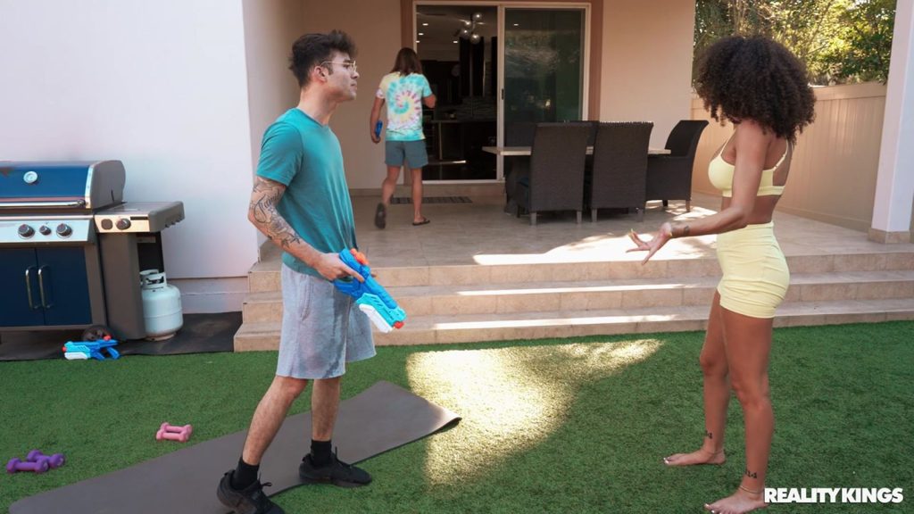 Far away side view of black Yoga girl angry at a guy holding a water gun