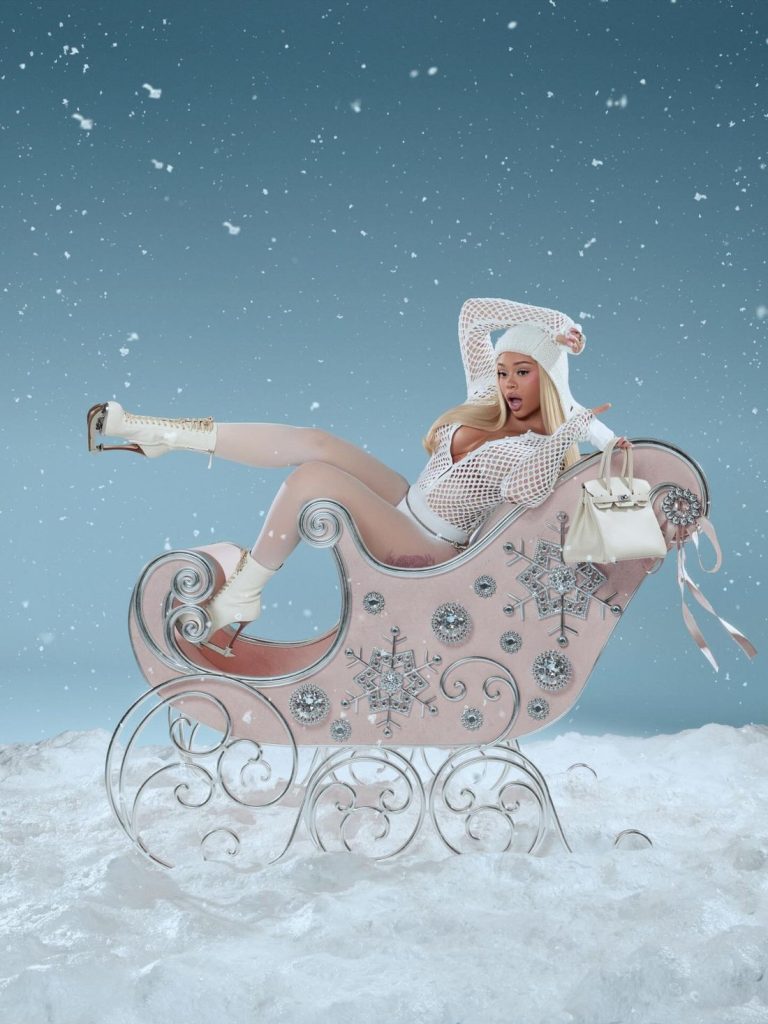 Far away view of Latto sitting back in a big winter sled wearing skates