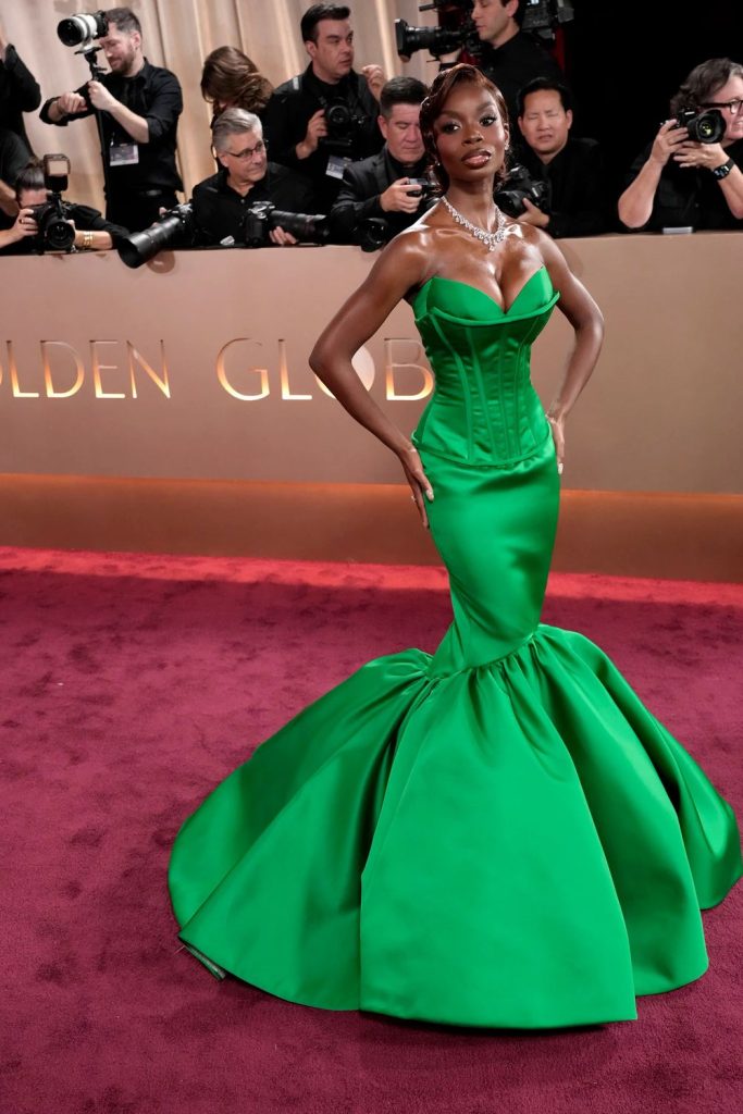 Full body frontal of black woman in a glamour dress posing in front of photographers on a red carpet