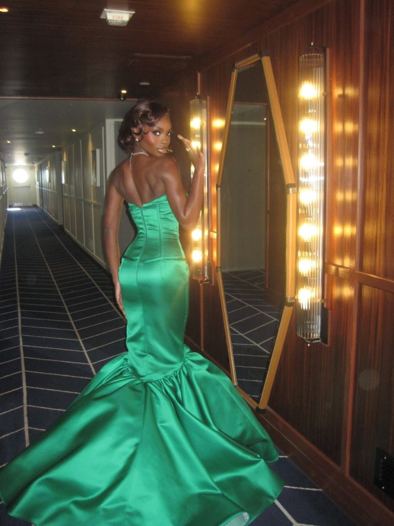 Full body backside view of black woman looking back over her shoulder while posing in a hallway