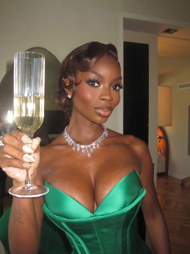 Close up frontal of black woman showing cleavage and holding a glass of champagne