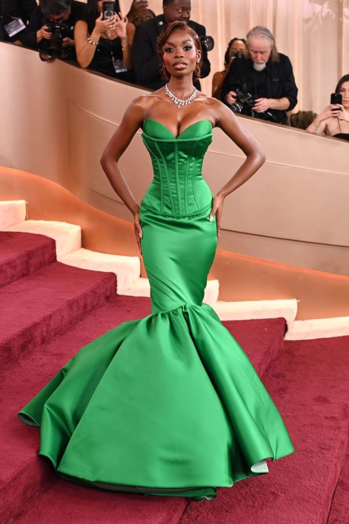 Full body frontal of black woman in a glamour dress posing on a red carpet staircase