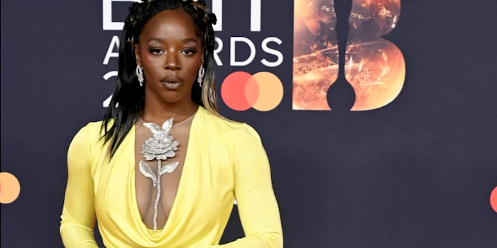 Close up of black woman posing in a yellow dress on the red carpet.