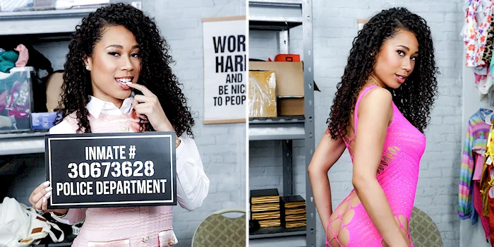 A woman with curly hair poses in two side-by-side images: on the left, she holds an inmate sign and bites her finger; on the right, she wears a revealing pink dress, looking over her shoulder in a storage room.