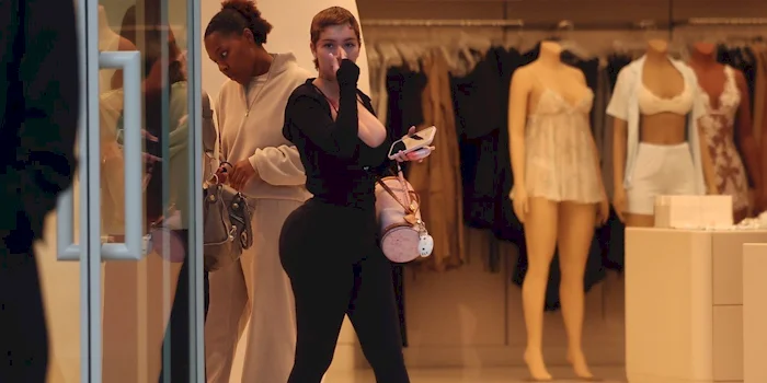 Two woman exit a clothing store wearing black leggings and a black top.