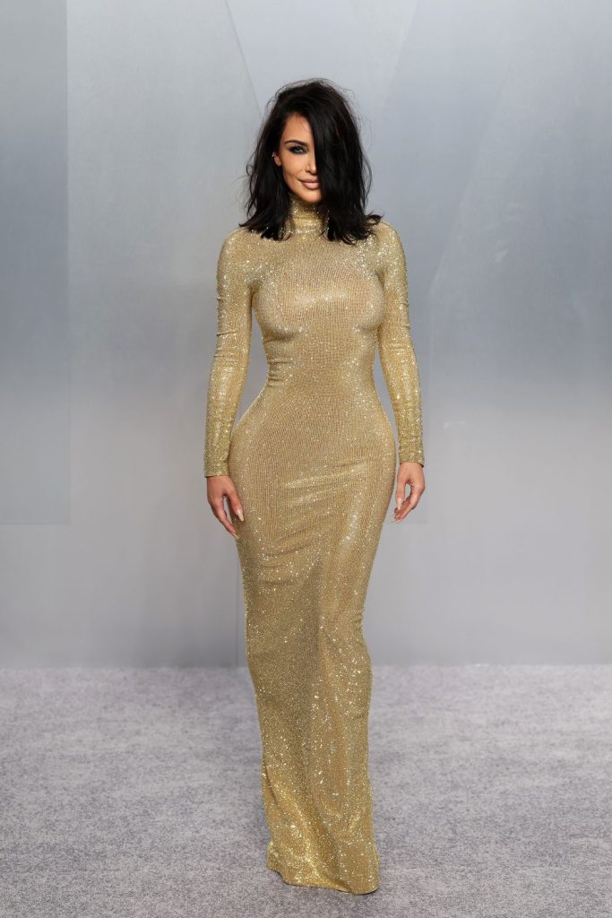 Kim Kardashian showing curvy figure in elegant gold gown at event.