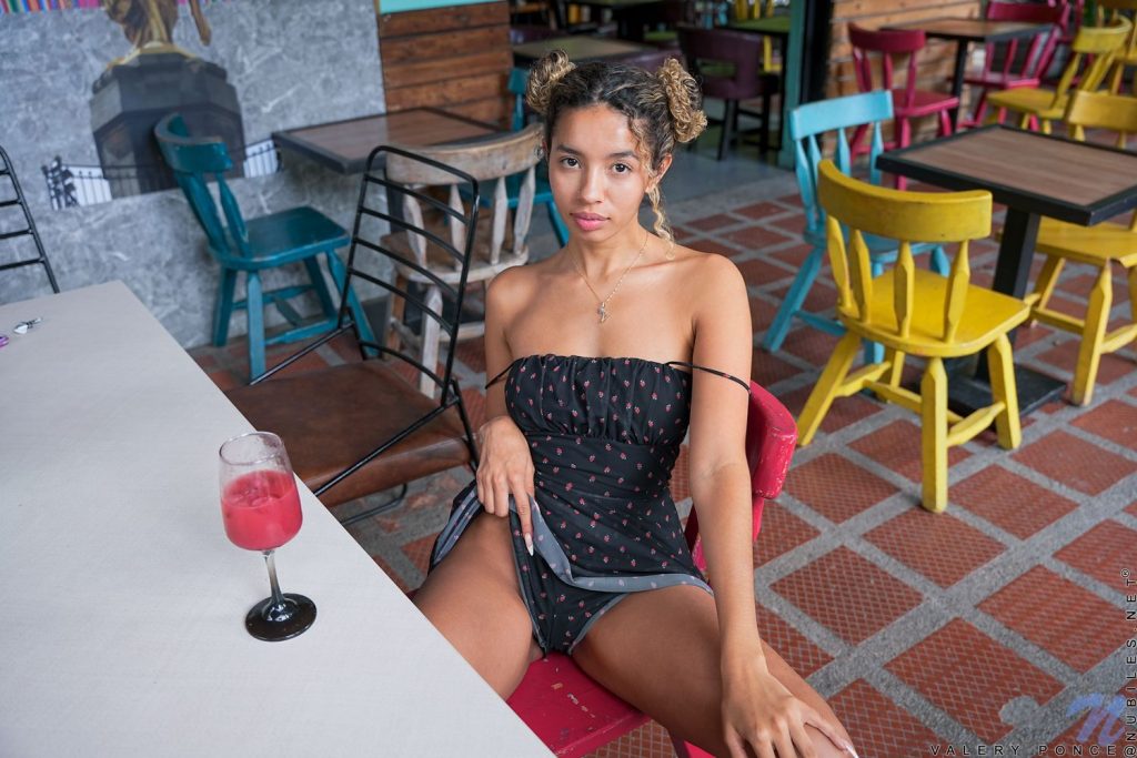 Woman lifting up her dress while sitting at colorful restaurant table.
