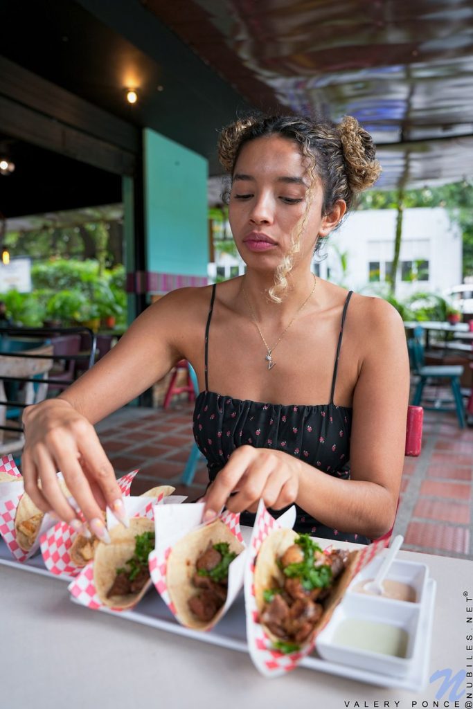 Woman grabbing tacos while sitting at a table in a restaurant