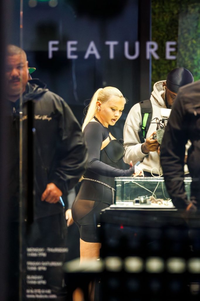 Profile view of a girl wearing tight black shorts standing in front of the counter inside a store looking at products.