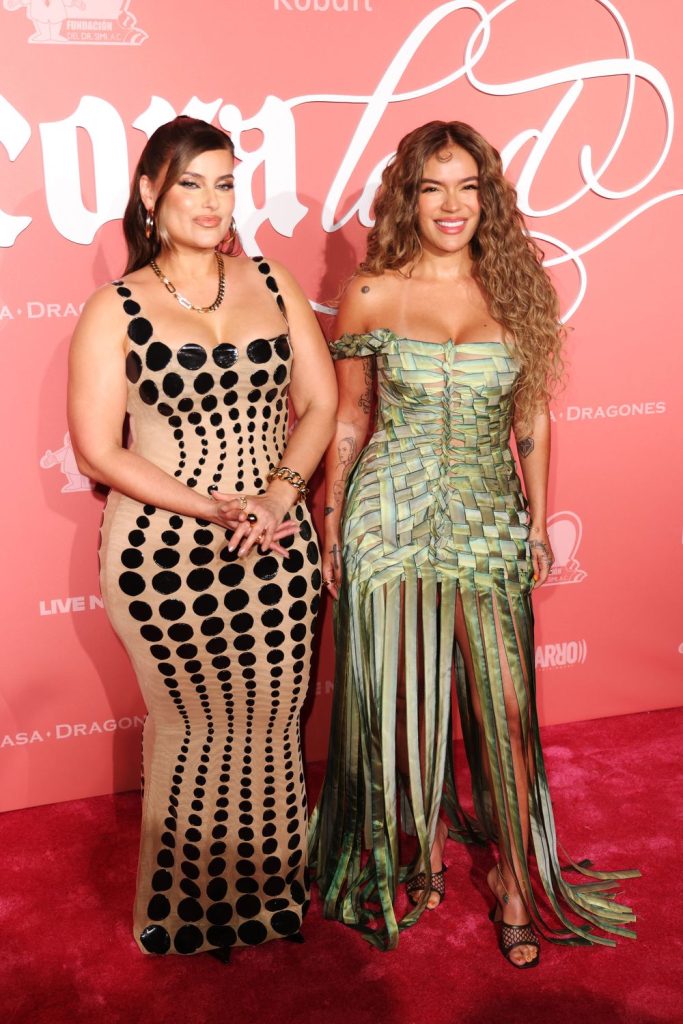 Two women in beautiful dresses posing together on a red carpet.