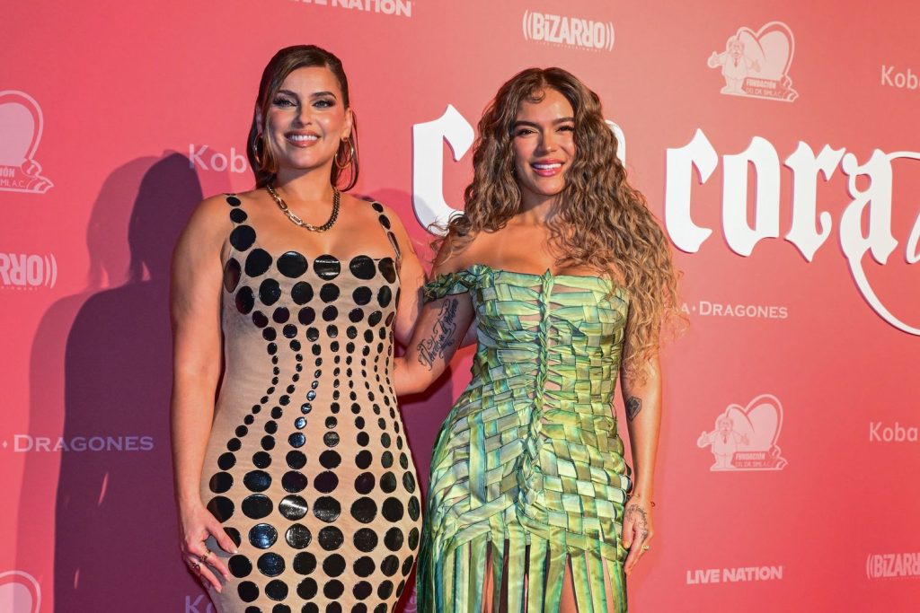 Two women standing side by side embracing each other on a red carpet.
