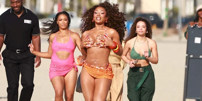 Megan Thee Stallion grabs her bikini boobs and smiles big when running on the beach.