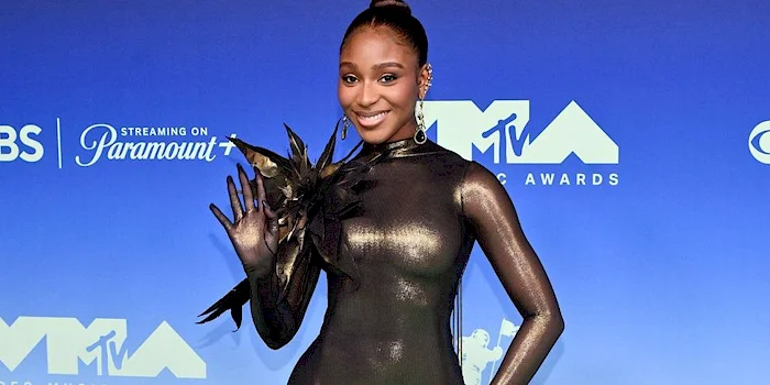 Normani poses on the MTV Video Music Awards red carpet wearing a metallic gold long-sleeved bodysuit.