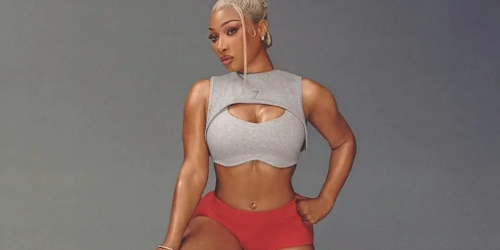 Megan Thee Stallion in a grey cropped tank top and red shorts.