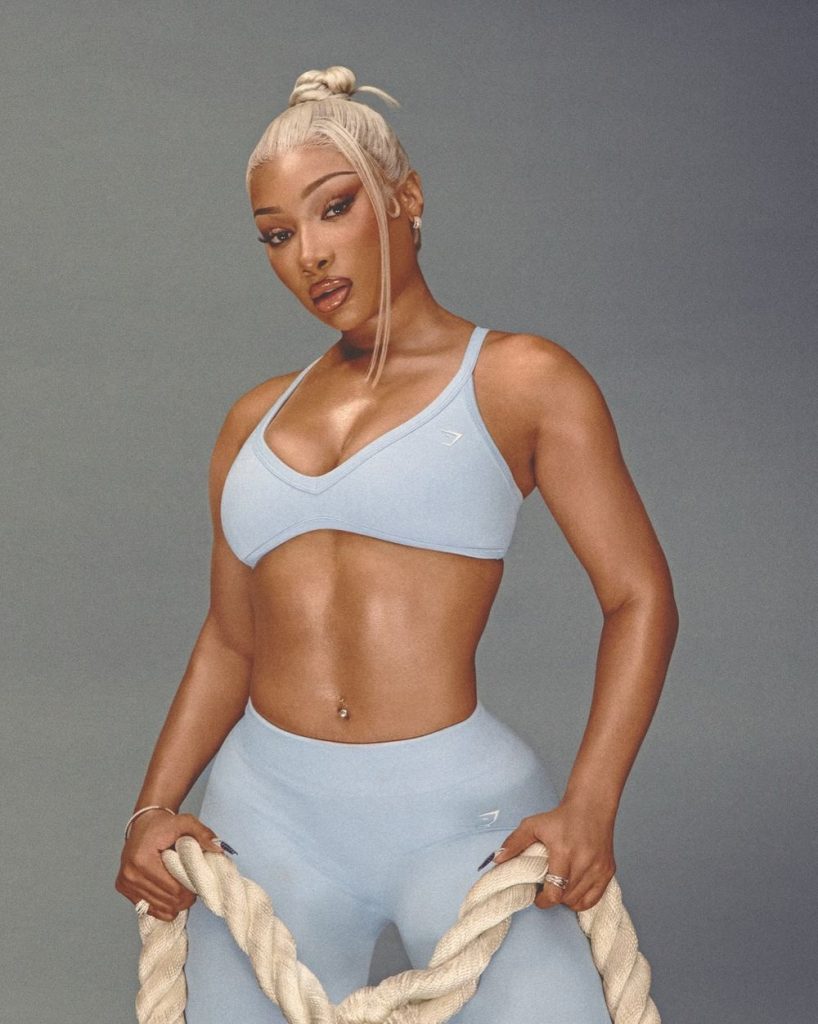 Megan Thee Stallion wearing a light blue sports bra and leggings, holding a rope.